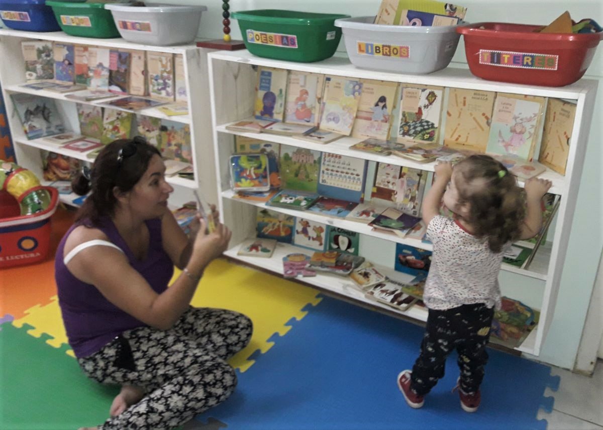 Photo of Personal de la Bebeteca mostrando libros a un niño en la Bebeteca